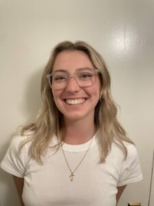 Anna Davidson, in a white shirt and necklace, smiles