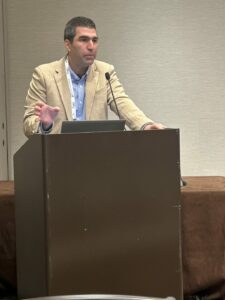 A photo from Building Innovation 2025 shows Emre Toprak at a podium.