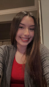 Kelsey Medina, in a red shirt, smiles 