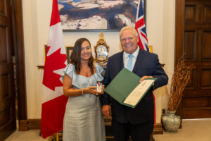 Lora (left) receives the the King’s Coronation Medal from the premier of Ontario.