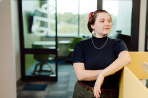 Rosalyn Becicka leans against a cubicle wall.