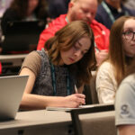 A woman takes notes during an IIBEC education session.