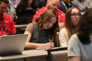 A woman takes notes during an IIBEC education session.